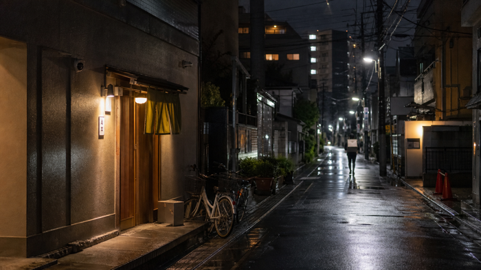 雨の夜の街を歩くデリバリーの配達員